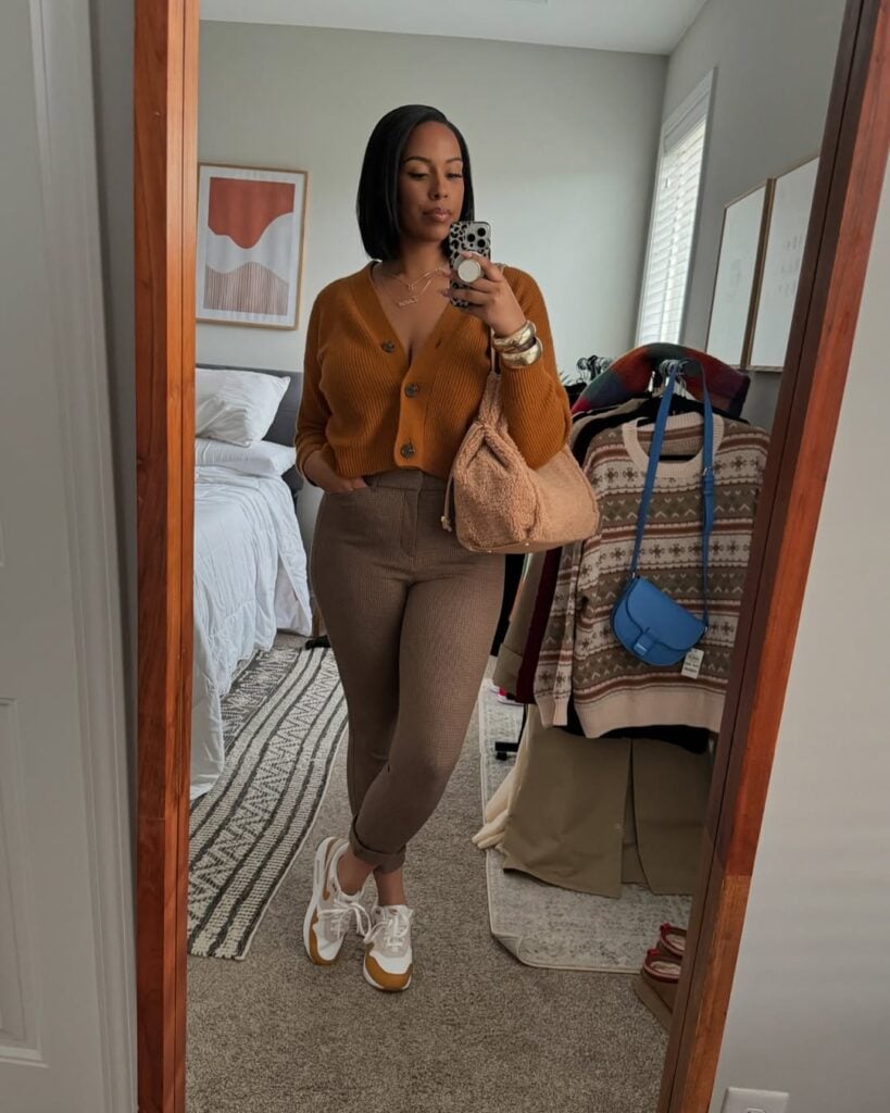 Mulher jovem com tênis casual, calça marrom e suéter laranja