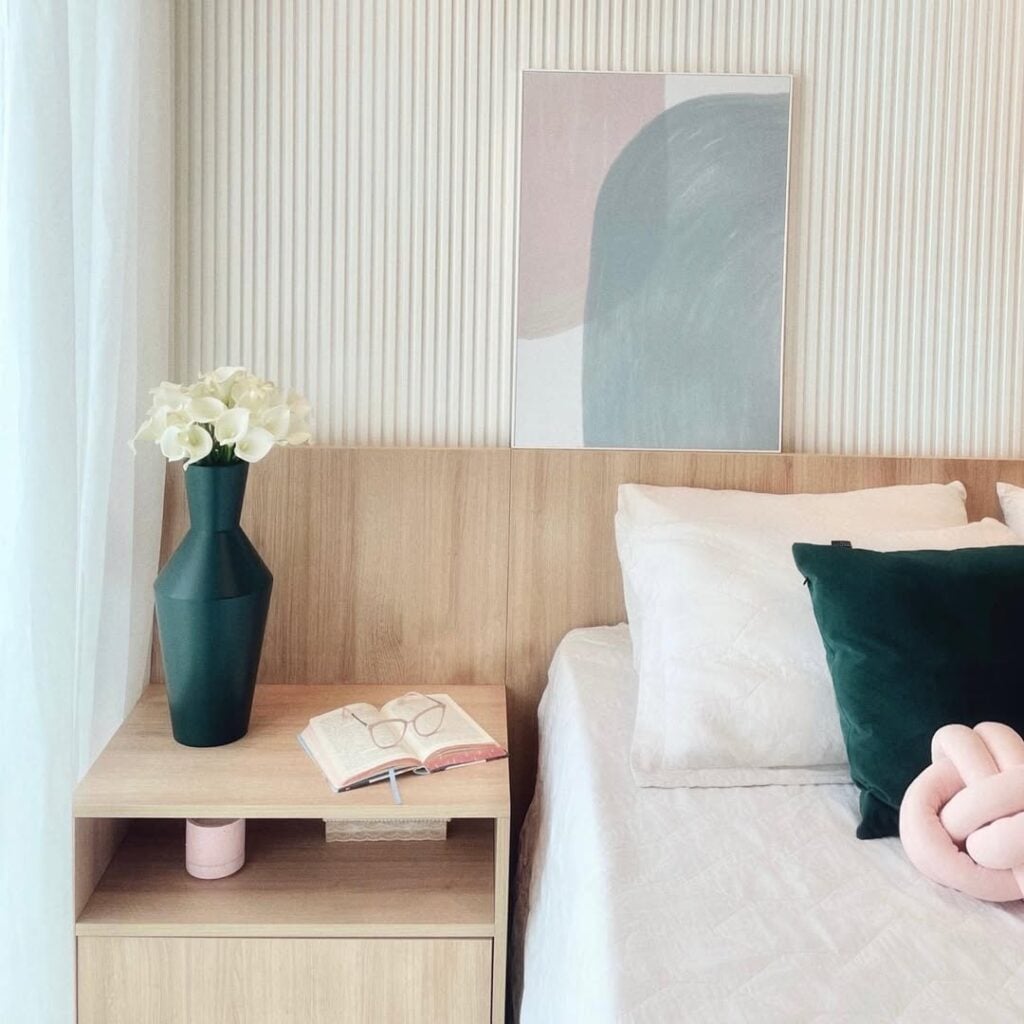 Quarto com cabeceira em madeira clara e ripado branco atrás