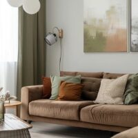 Sala com sofá em suede marrom com almofadas verde e terracota