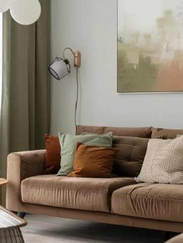 Sala com sofá em suede marrom com almofadas verde e terracota