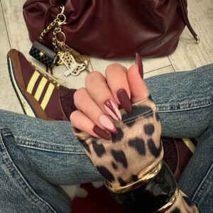 Mão de pele clara, com unha burgundy decorada