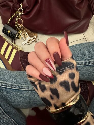 Mão de pele clara, com unha burgundy decorada