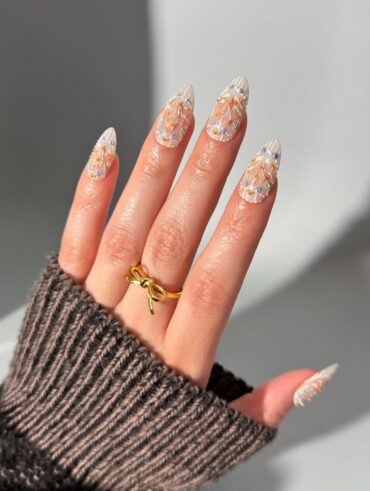 Mão de pele clara, com anel dourado e unha amendoada com design de bolo de aniversário