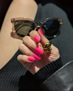 Mão de pele clara, com anel em dourado e unha amendoada rosa