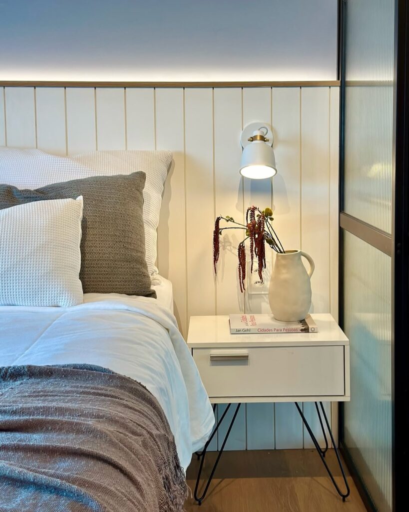 Quarto com mesa de cabeceira branca e divisória com vidro canelado