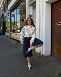 Mulher jovem com look com casaco de poá e bermuda jeans