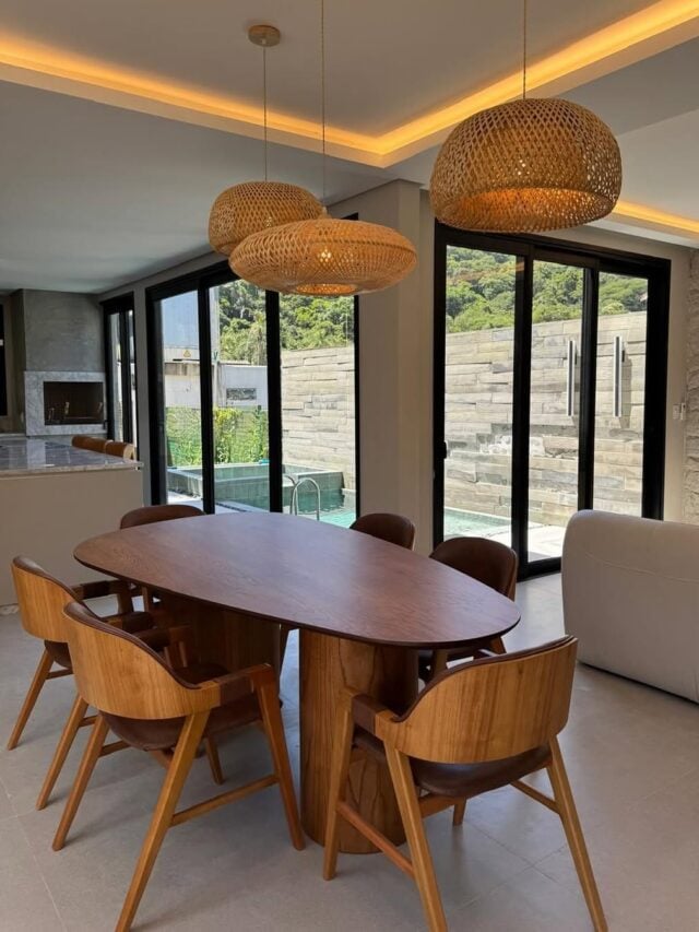 Sala de jantar com mesa e cadeiras de madeira e pendentes de fibras naturais