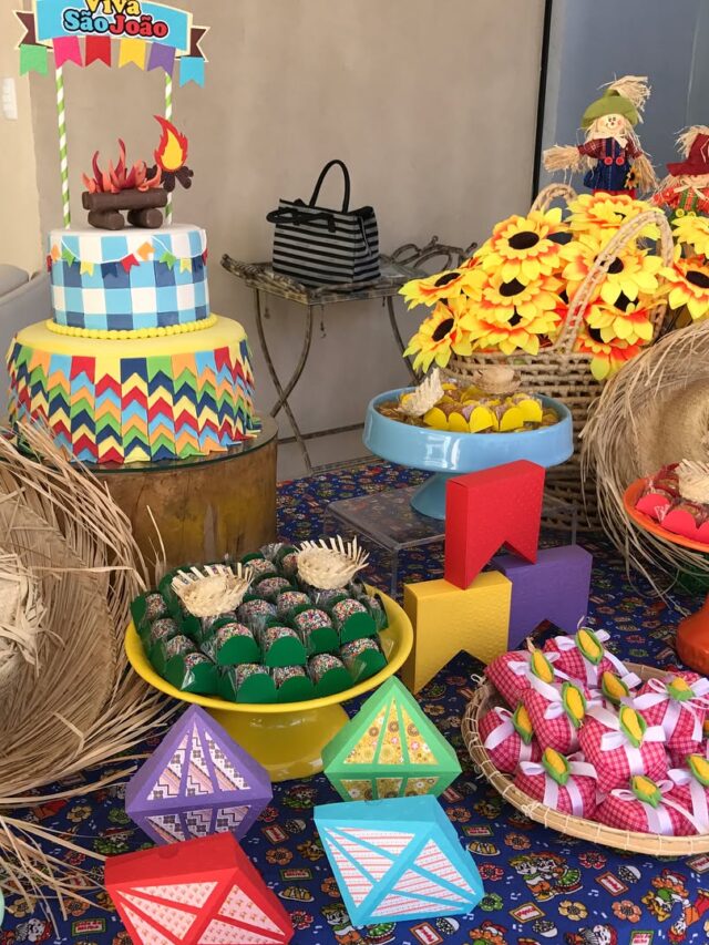 Mesa com balões de papel, arranjo com girassóis, docinhos decorados