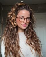 Mulher de pele clara, com blusão cinza, cabelo ondulado e maquiagem simples