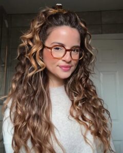 Mulher de pele clara, com blusão cinza, cabelo ondulado e maquiagem simples