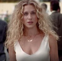 Carrie Bradshaw, com vestido branco e cabelo loiro cacheado