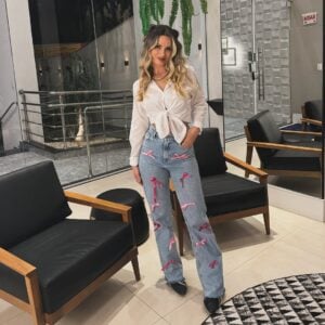 Mulher de pele clara, com calça jeans com laços e camisa branca amarrada