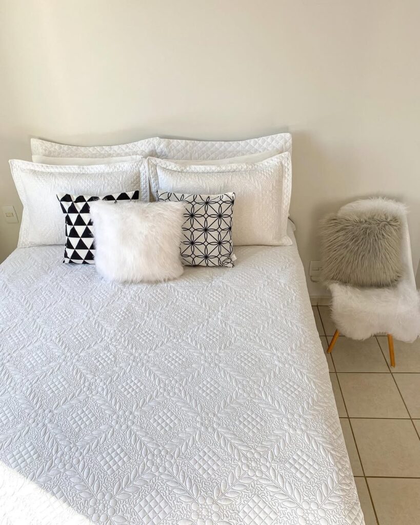Cama posta branca com almofadas e detalhes pretos