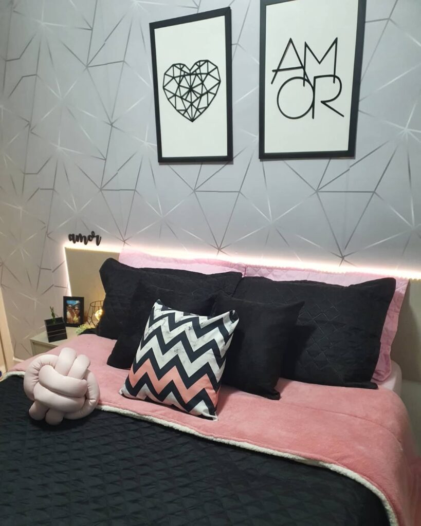 Quarto com papel de parede cinza com figuras geométricas, cabeceira com led e cama posta com almofadas e edredom preto