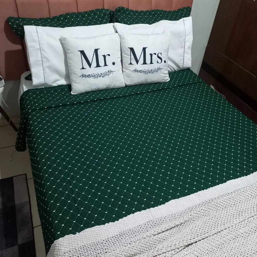 Quarto de casal com cama posta verde e almofadas brancas com monogramas em preto