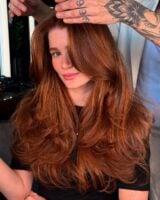 Mulher de pele clara, com blusa preta e cabelo ruivo