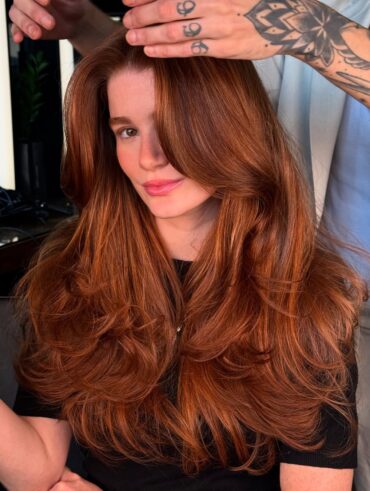 Mulher de pele clara, com blusa preta e cabelo ruivo