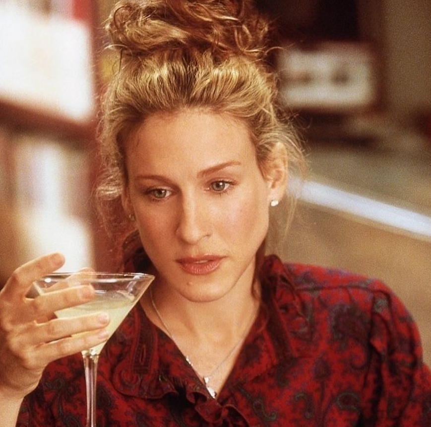 Carrie Bradshaw, com blusa vermelha e coque