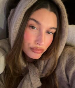 Hailey Bieber, com look de tricot e cabelo castanho