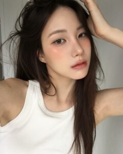 Mulher de pele clara, com regata branca e cabelo castanho