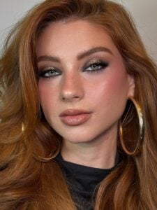 Mulher de pele clara, com cabelo ruivo e maquiagem clean
