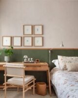Quarto com meia parede verde e escrivaninha de madeira ao lado da cama