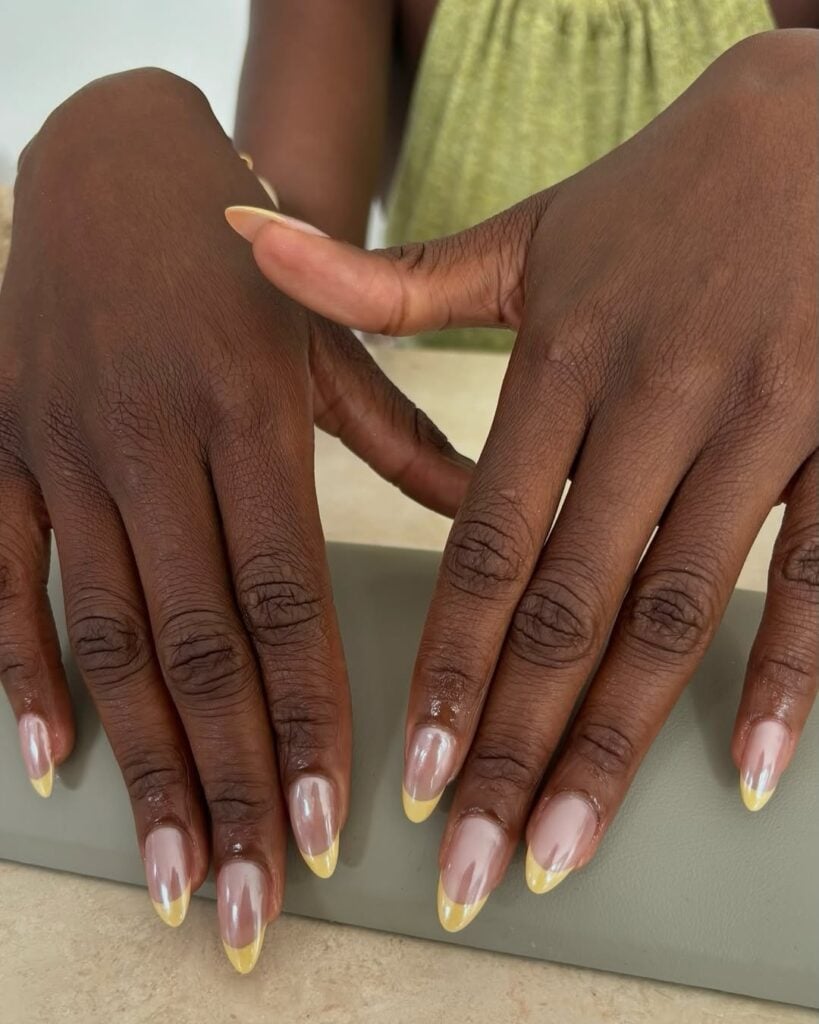 Mãos de pele preta, com unha amendoada com inglesinha amarelo-manteiga 