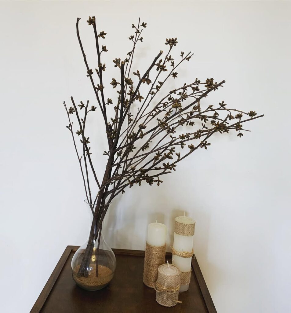 Mesa com velas e vaso transparente com galhos secos