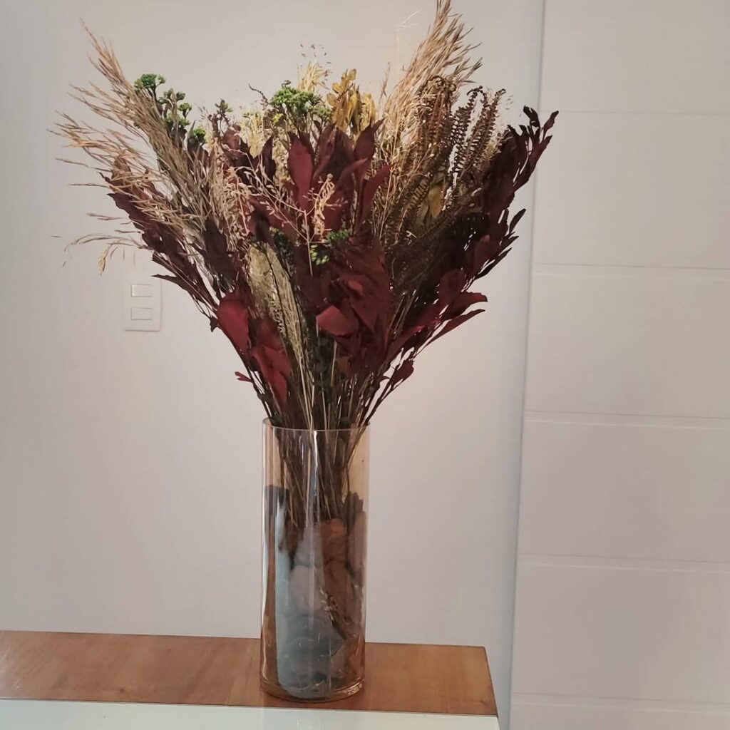 Vaso de vidro com galhos secos bege e marrom