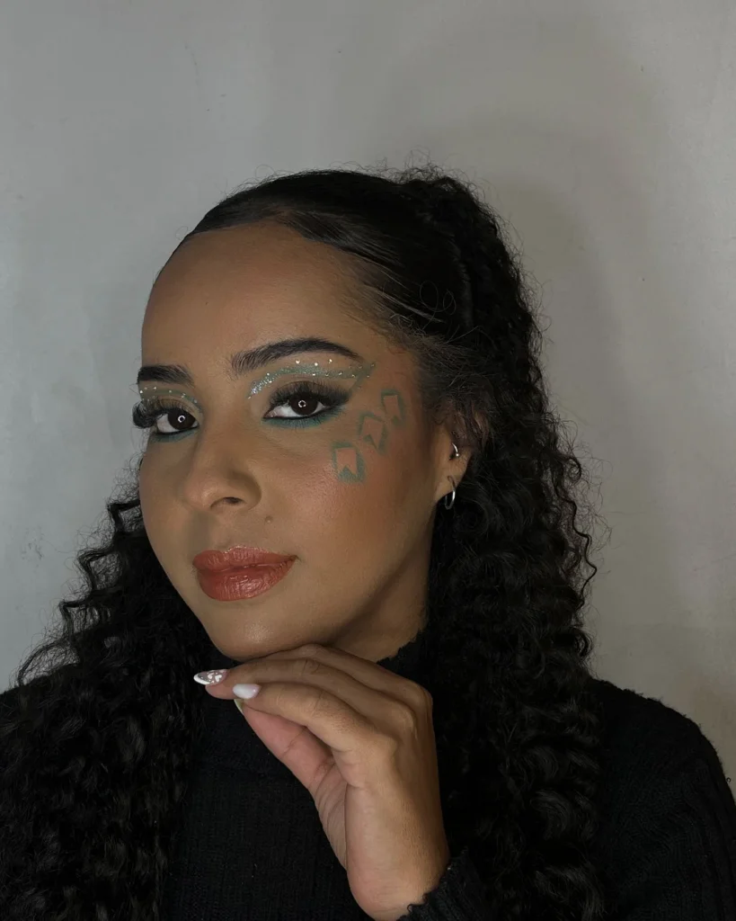 Mulher de pele preta, com cabelo cacheado e maquiagem em tons de azul