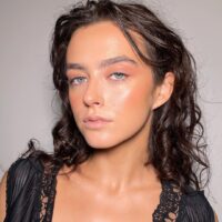Mulher de pele clara, com cabelo escuro e maquiagem clean