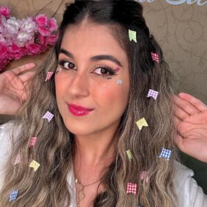 Mulher de pele clara, com cabelo loiro com bandeirinhas e maquiagem de São João