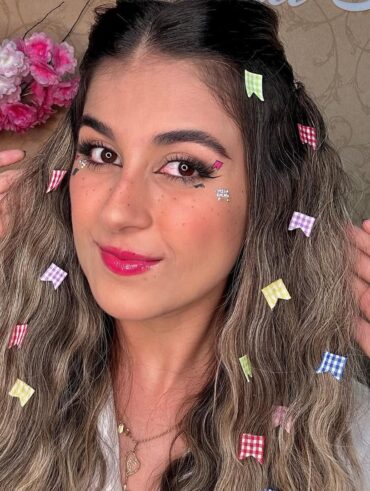Mulher de pele clara, com cabelo loiro com bandeirinhas e maquiagem de São João
