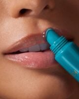 Mulher de pele clara, aplicando lip balm nos lábios