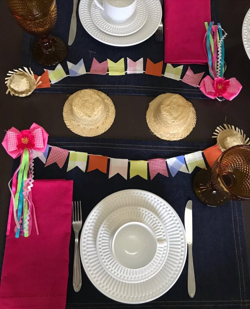 Mesa posta com bandeirinhas e chapéus de palha