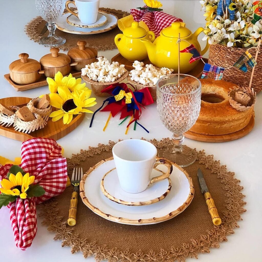 Mesa posta com louça branca, guardanapos xadrezes em vermelho e branco. mini chapéus com pipoca