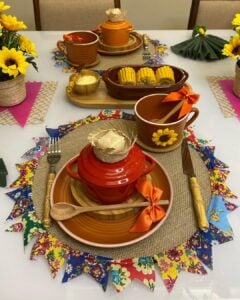 Mesa posta de café da manhã junino com jogo americano de juta e bandeirinhas coloridas