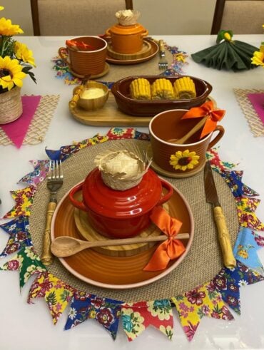 Mesa posta de café da manhã junino com jogo americano de juta e bandeirinhas coloridas