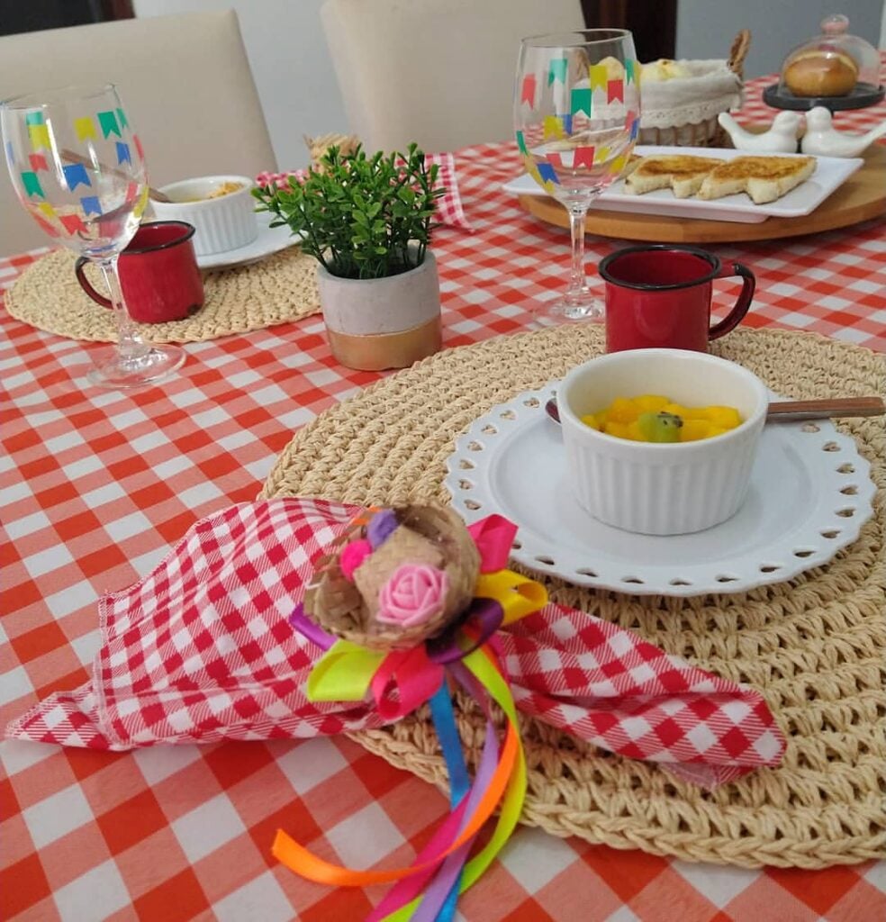 Mesa com toalha xadrez em vermelho e branco, guardanapo xadrez com mini chapéu e fitas