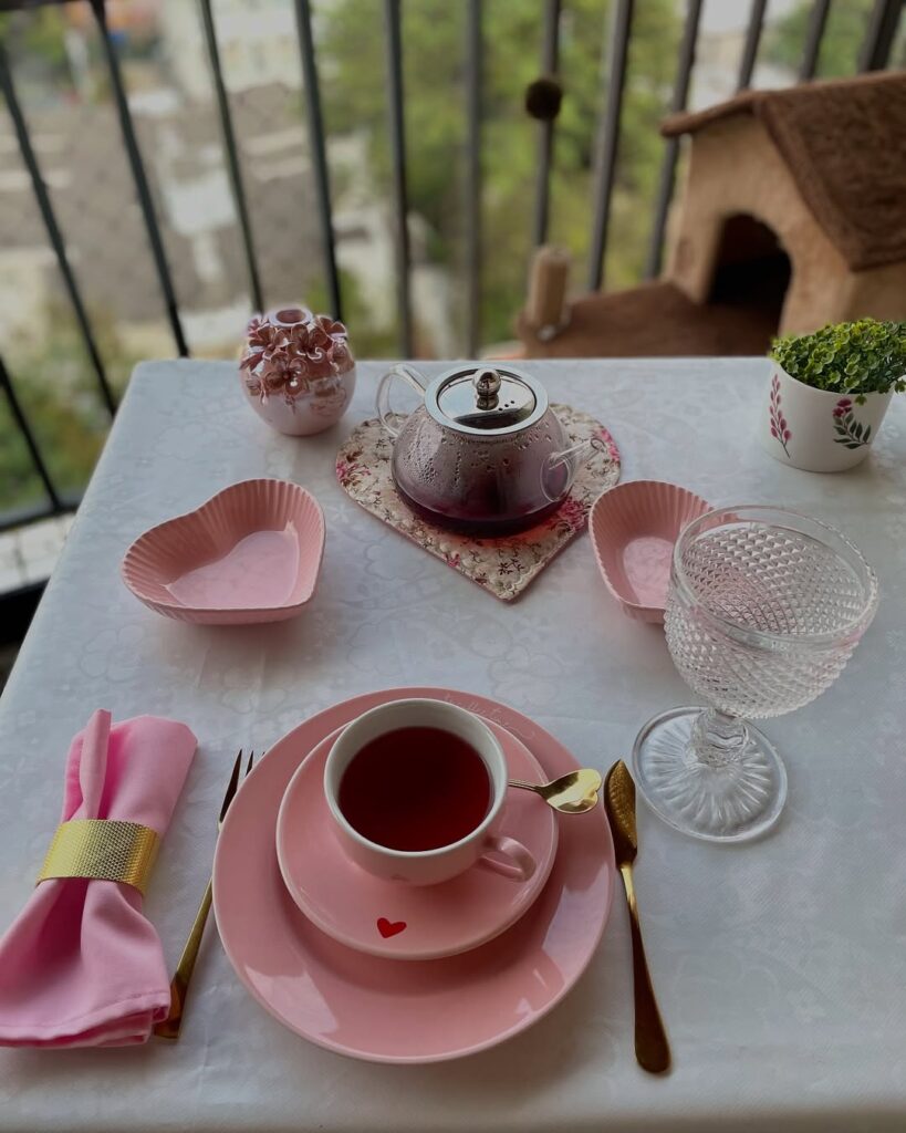 Mesa posta de chá com prato, pires e xícara rosa com coração vermelho