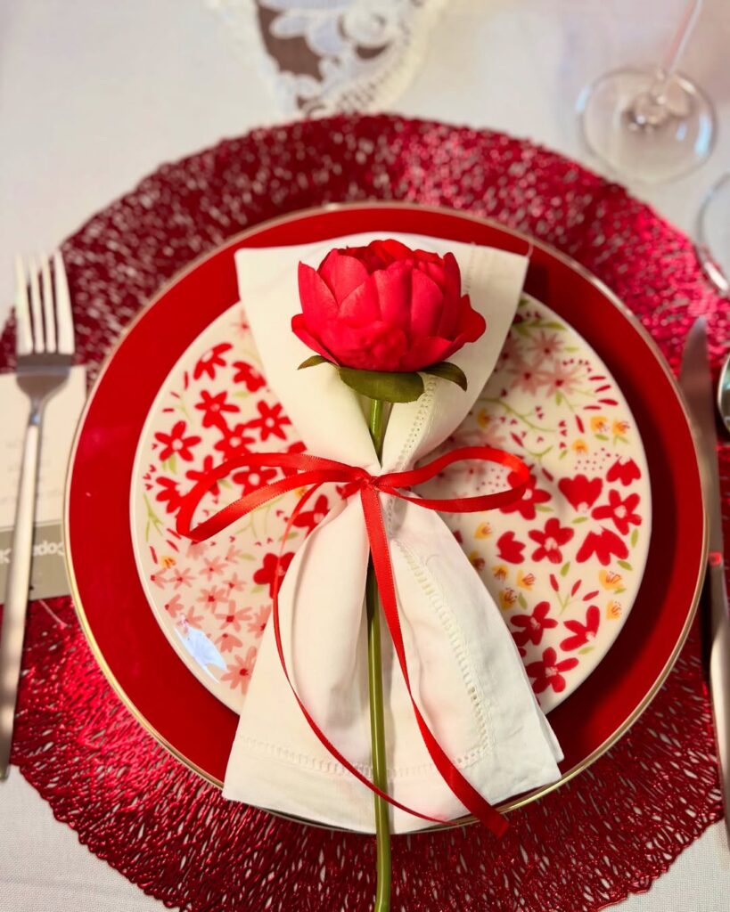 Sousplat vermelho, prato vermelho e guardanapo com rosa vermelha
