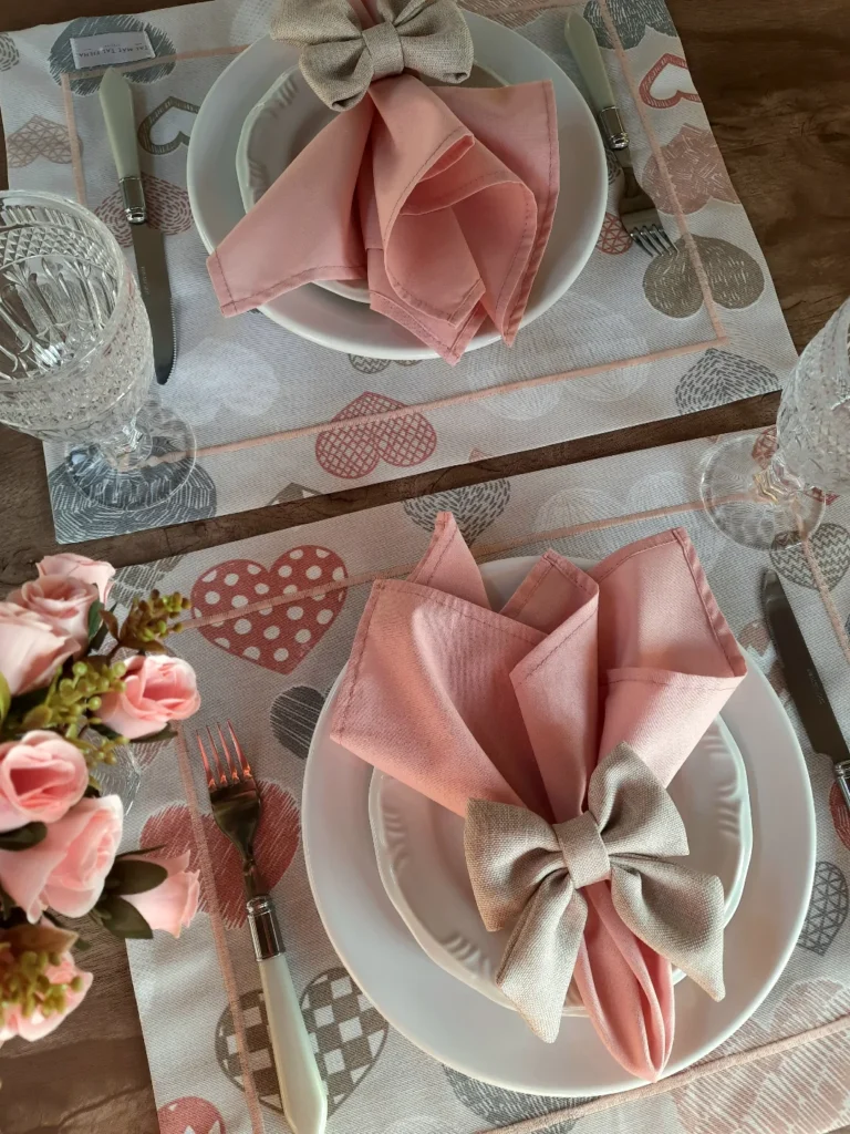Mesa posta romântica com jogo americano com corações, guardanapo rosa e laço bege