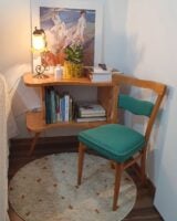 Estante com livros e luminária e cadeira de madeira com assento e encosto em tom de azul