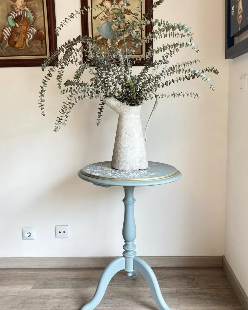 Mesinha azul-claro com borda dourada e vaso com planta
