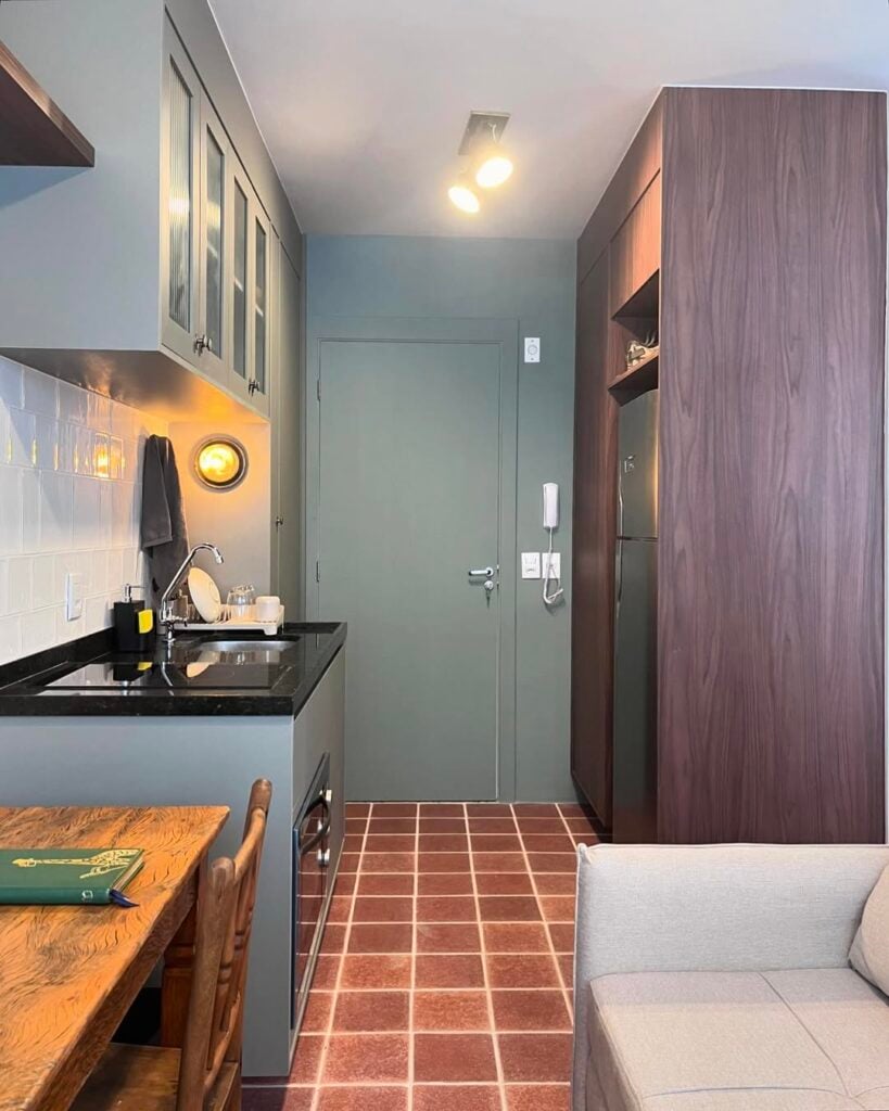 Cozinha com piso cerâmico marrom, armários e porta em tom de cinza