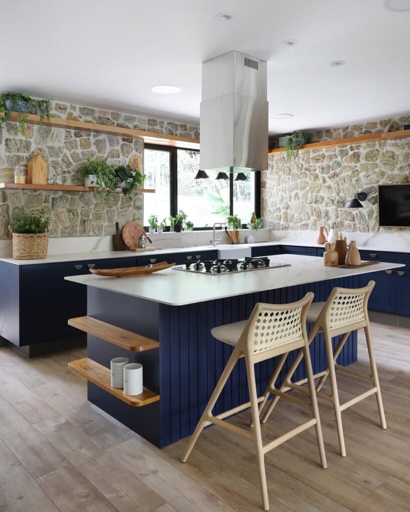 Cozinha com porcelanato e madeira com armários azul-marinho e ilha