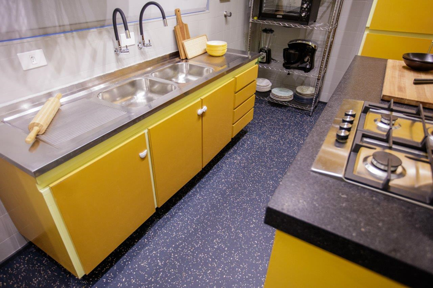 Cozinha com armário amarelo e piso vinílico azul-marinho