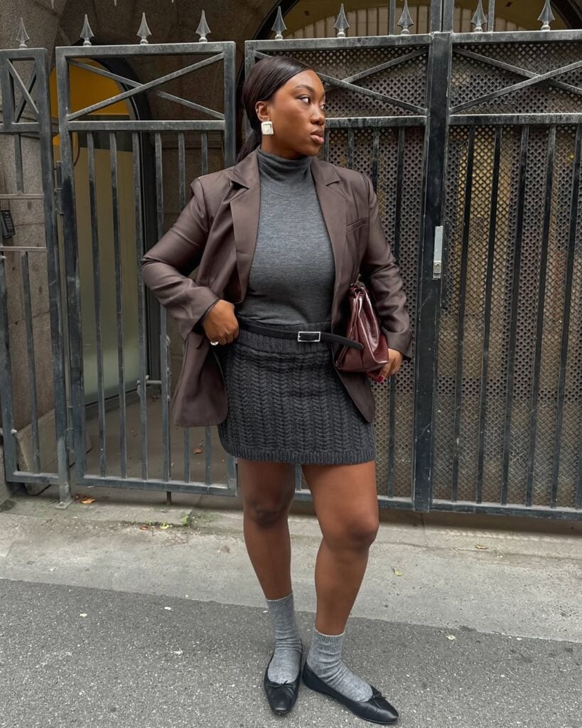 Look com blazer marrom, saia cinza, suéter cinza e sapatilha preta