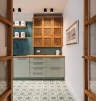 Cozinha com armário cinza e puxadores pretos, armário de madeira, azulejo azul na parte da pia e piso com outro padrão