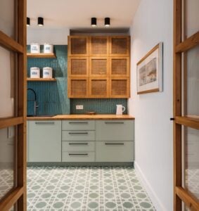 Cozinha com armário cinza e puxadores pretos, armário de madeira, azulejo azul na parte da pia e piso com outro padrão